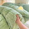 A hand is touching a soft, light green rabbit fleece duvet cover on a bed.
