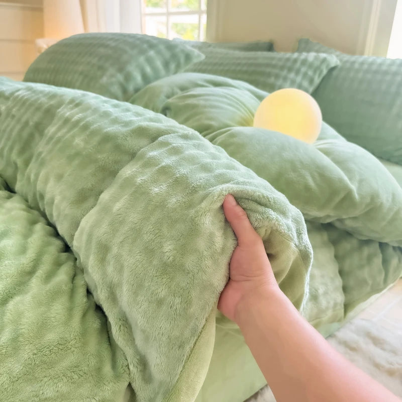 A hand is touching a soft, light green rabbit fleece duvet cover on a bed.