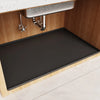 A dark silicone mat liner is placed inside a wooden under sink cabinet for waterproofing.
