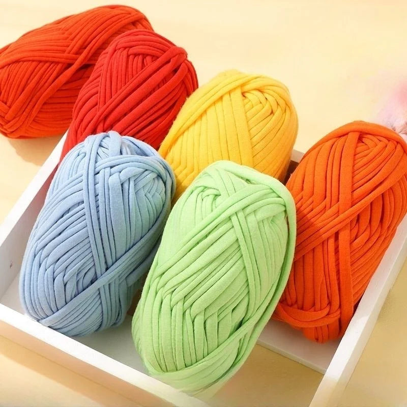 A collection of brightly colored flat thread yarn skeins in shades of orange, red, yellow, and blue arranged in a white box.