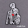 Black and white embroidered skull design featuring two skulls with a red heart between them