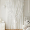 White vintage ruffled lace embroidered curtain hanging in a bright room.