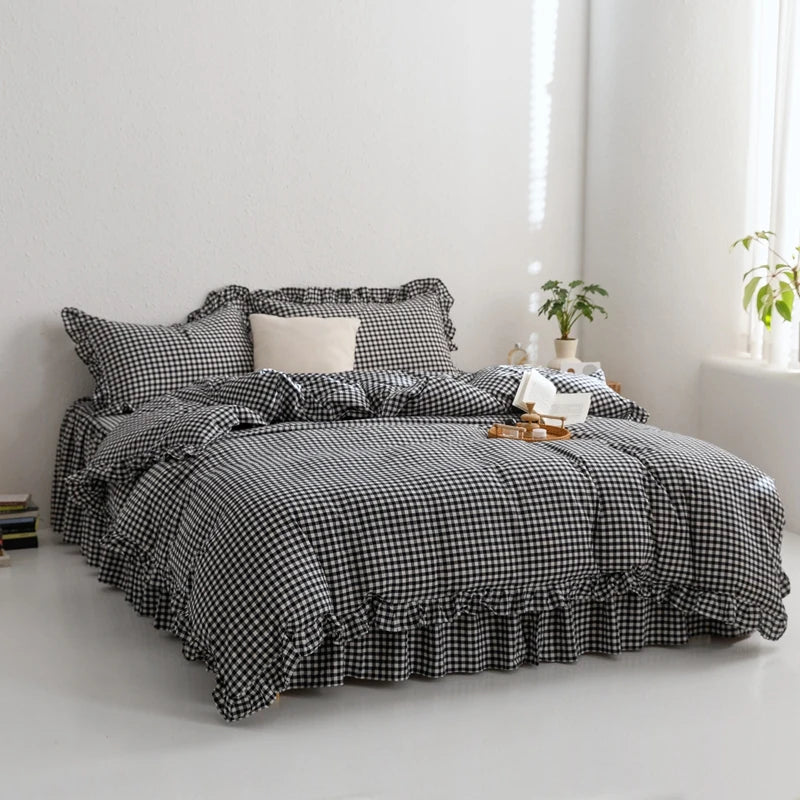 A black and white plaid duvet cover set with a solid cream pillow on a bed.