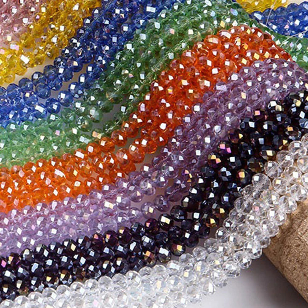 A close-up of multicolored faceted rondelle glass beads arranged in a wavy line.