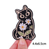 Black embroidered cat patch with white flowers and green leaves on a hand