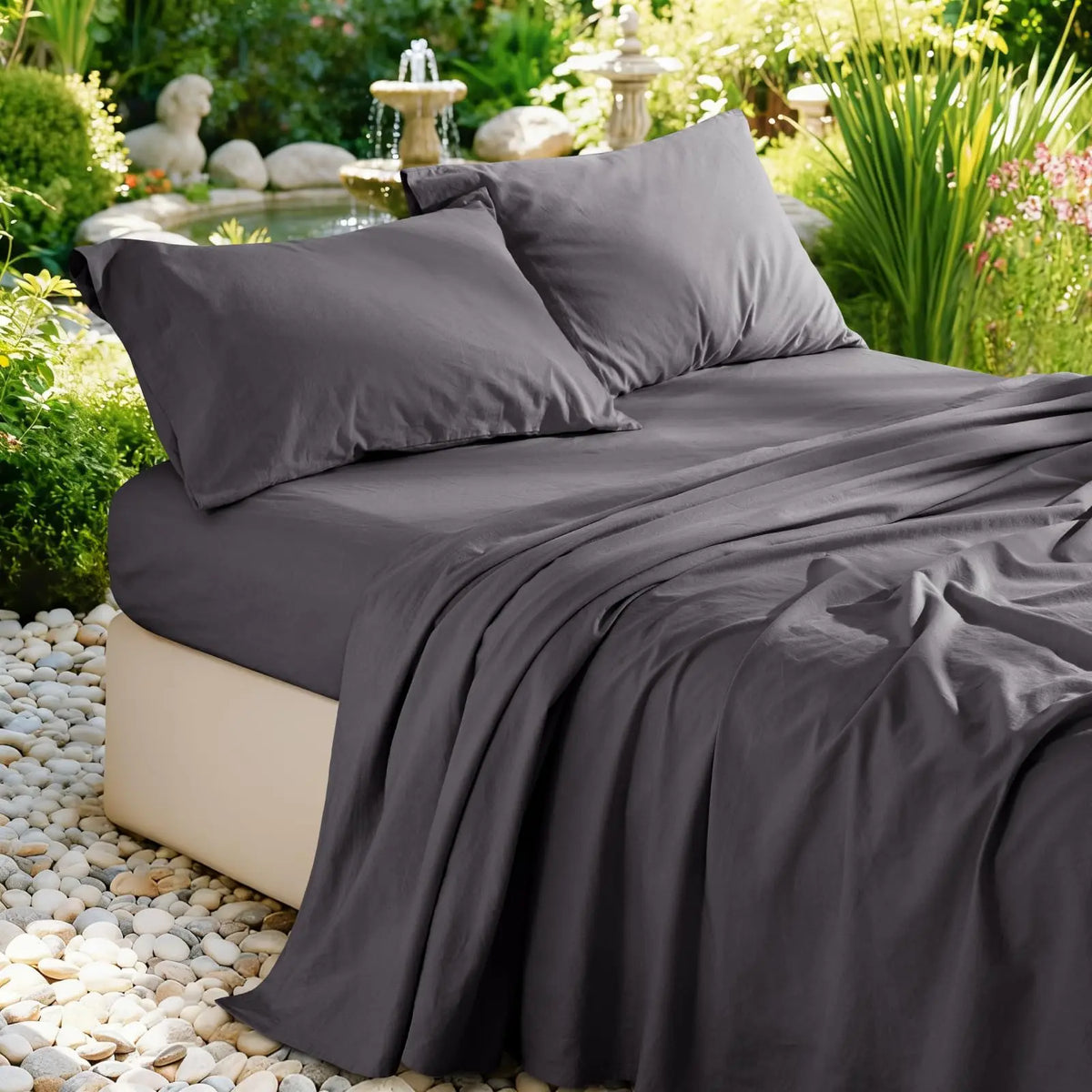A dark gray pure French linen bed sheet draped over a bed in a lush garden setting.