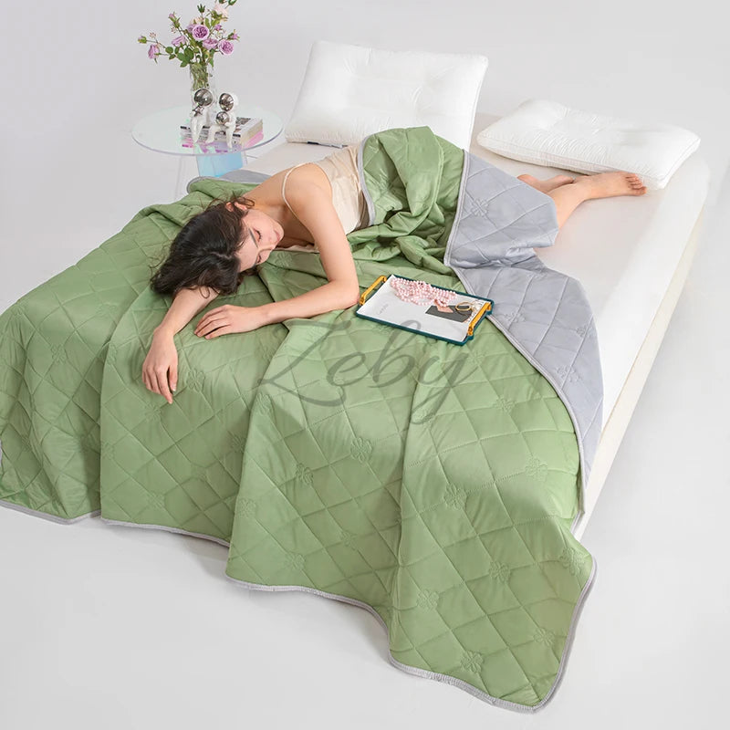 A person is lying on a light green quilted blanket indoors with a white pillow and a small potted plant.