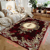A deep red luxury floral area rug with gold accents placed on a wooden floor.