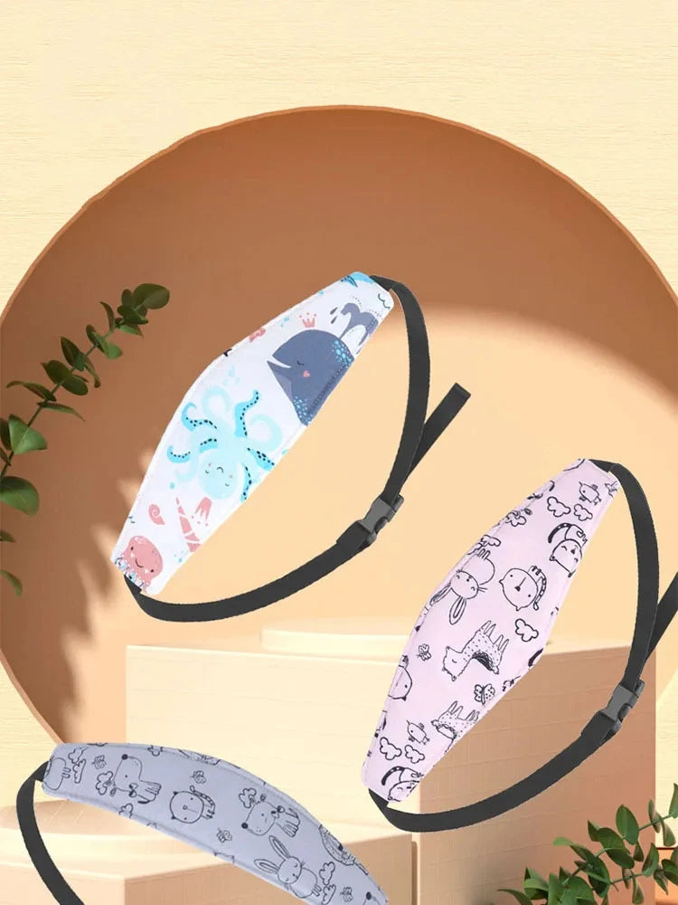 A pink and blue patterned baby head and neck support pillow is shown resting on a light brown surface.