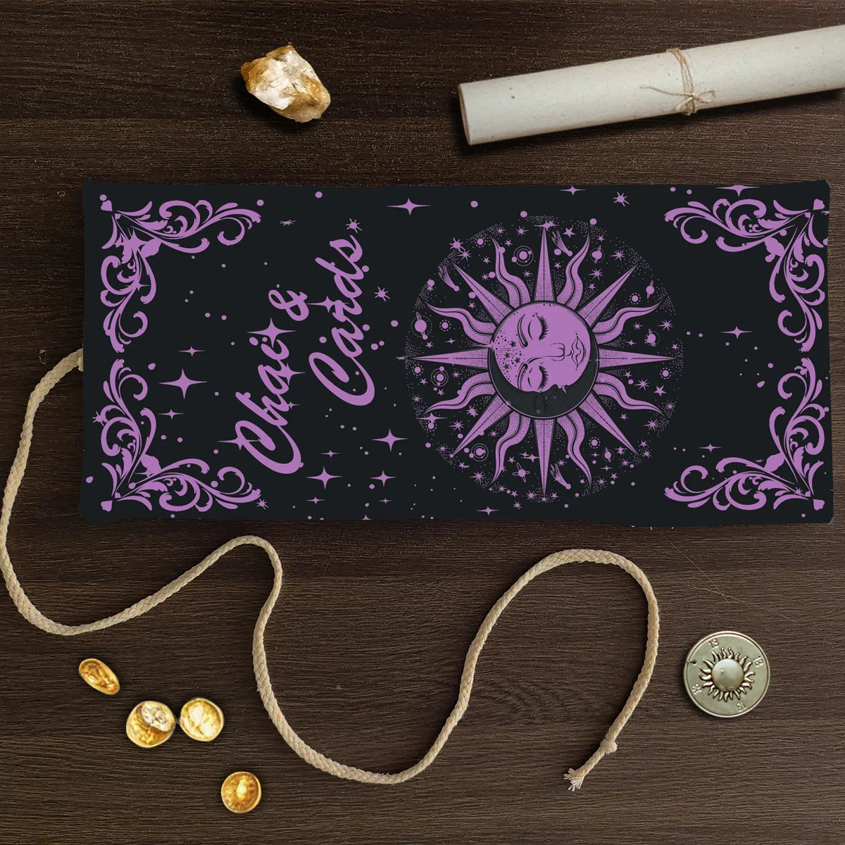 A dark purple tarot card storage pouch featuring a sun motif and floral borders, laid on a wooden surface with twine.