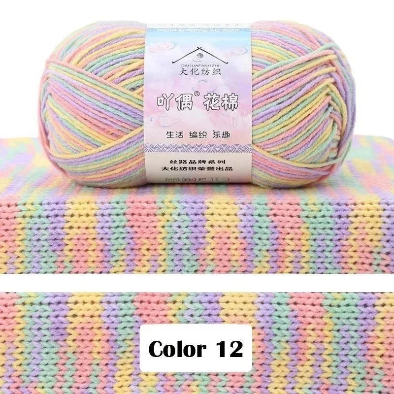 A ball of multi-colored yarn with pink, yellow, and green hues resting on a textured knit fabric background.