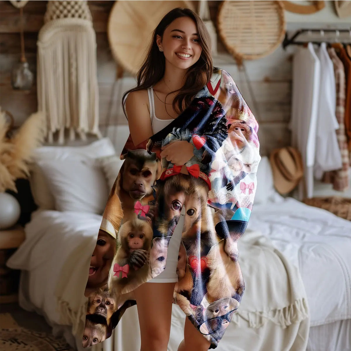 A woman models a funny monkey print flannel blanket draped over her, sitting on a white bed.