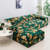 A dark green and gold tropical leaf patterned sofa protector cover displayed on a white round table.