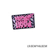 Pink embroidered letter patch spelling Motherhood on a black fabric background