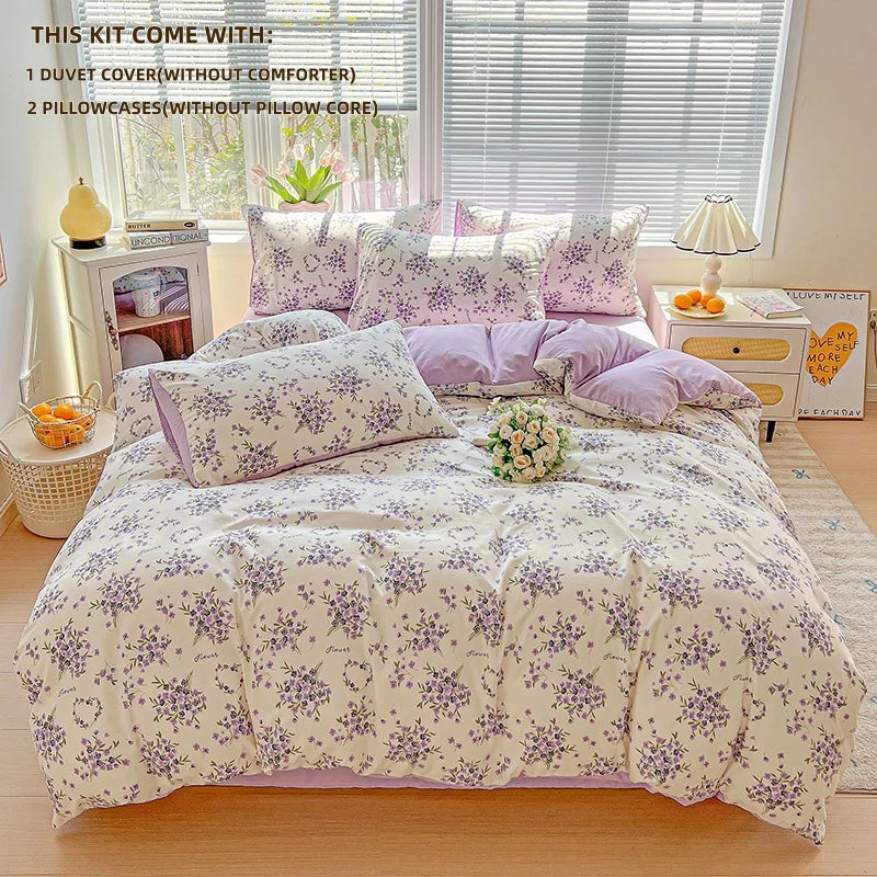 A lavender print duvet cover set with pillowcases displayed on a bed, next to a window and bedside tables.