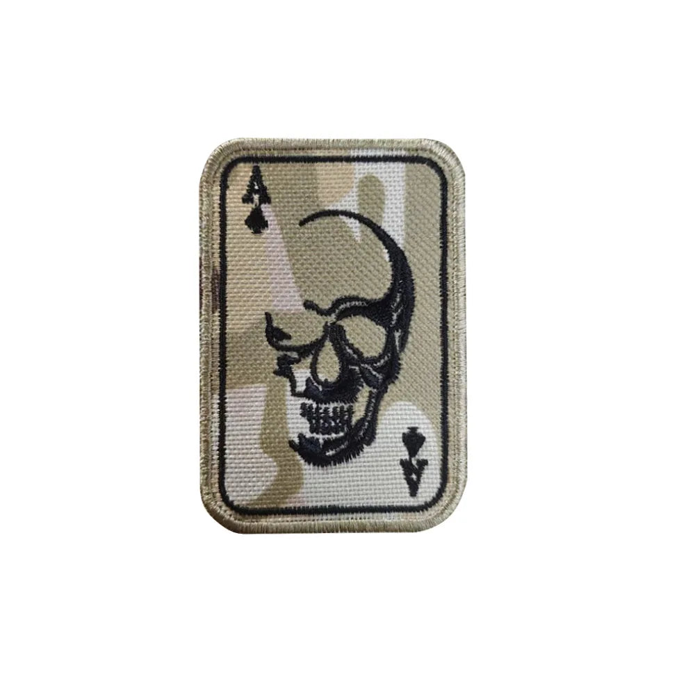 A rectangular embroidered patch featuring a skull design on a beige fabric background.