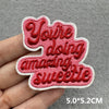 Red embroidered patch with the text Youre doing amazing sweetie on a hand