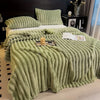 A thick, light green, ribbed flannel blanket is draped over a bed with matching pillows.