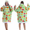 A person models a light green patchwork fleece hoodie with colorful fruit patterns.