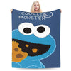 A dark blue blanket featuring a cartoon monster face with large eyes and an orange body.
