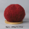 A ball of deep red mohair yarn used for crafting, displayed on a wooden base.
