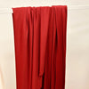 A vertical drape of solid red stretch fabric hanging against a white background.
