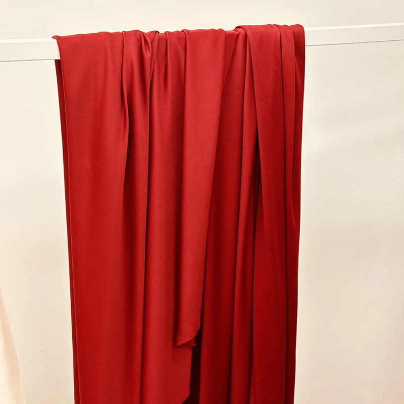 A vertical drape of solid red stretch fabric hanging against a white background.