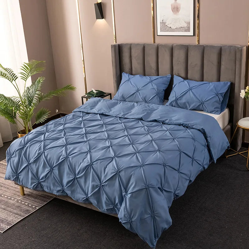 A blue quilted bedding set featuring a tufted headboard and matching pillows in a bedroom setting.