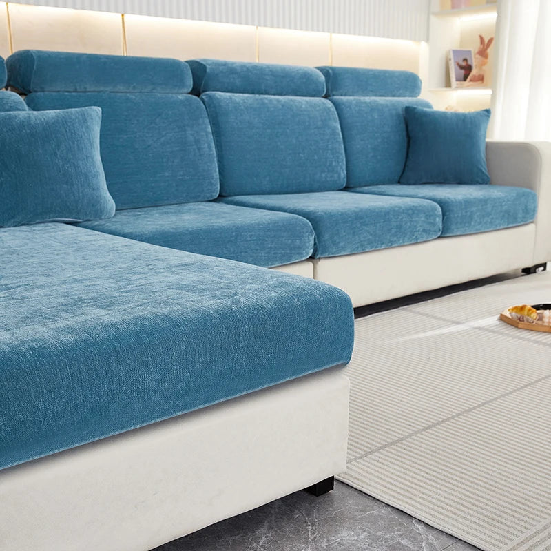 A teal stretchable chenille sofa cushion cover on a white sofa with light wood accents.