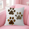 A white decorative pillow cover featuring a leopard print paw print design on a pink sofa.