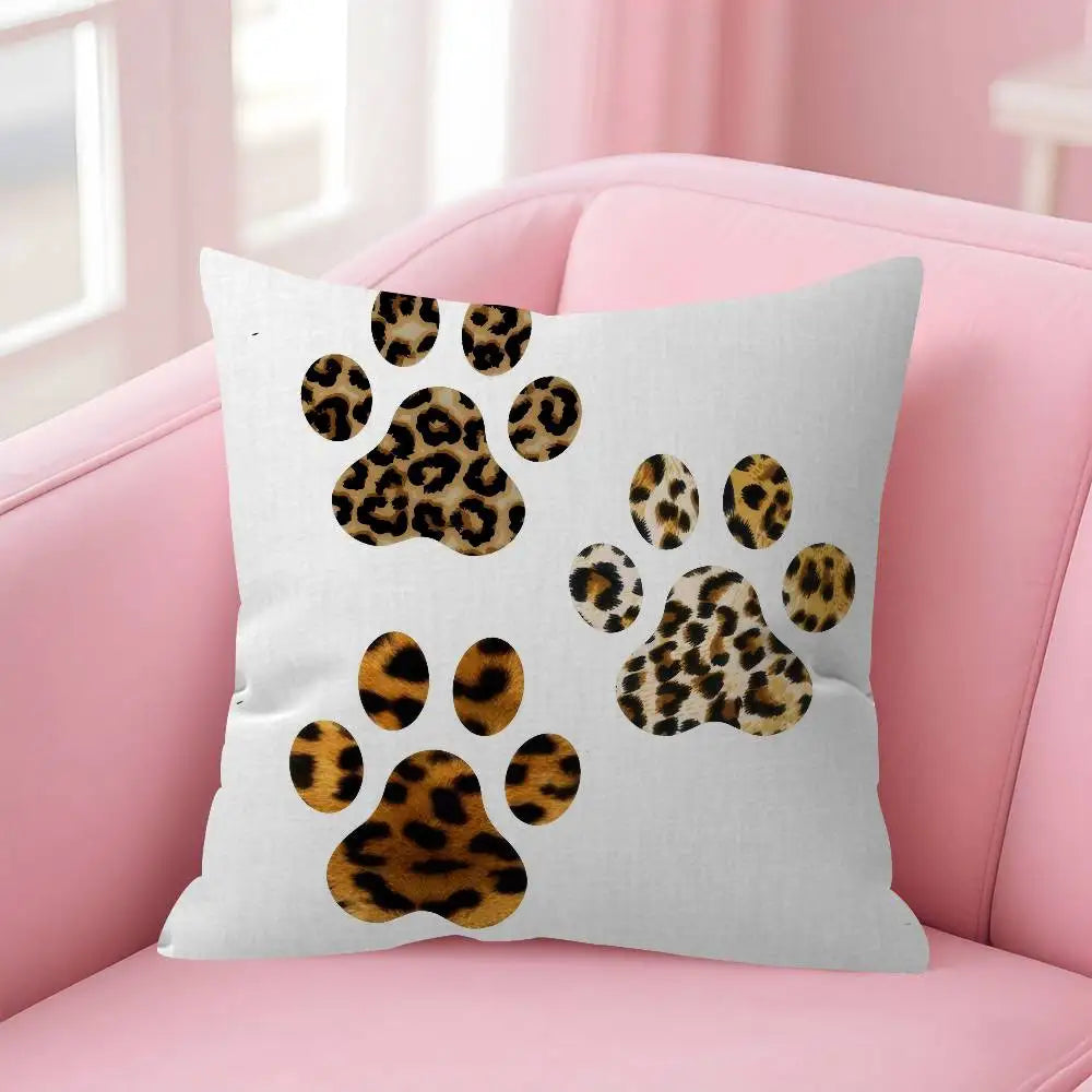 A white decorative pillow cover featuring a leopard print paw print design on a pink sofa.