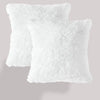 Two fluffy white velvet throw pillows stacked against a light gray background.