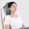A woman is resting her head on a gray memory foam U-shaped travel neck pillow in a white chair.