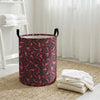 A purple leopard print foldable laundry basket sitting on a beige rug next to white towels.