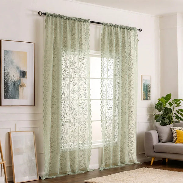 Light green lace floral sheer window curtains hanging in a bright room.