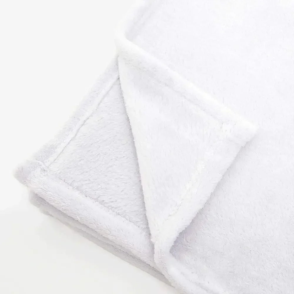 A white cozy flannel throw blanket folded and displayed on a light surface.