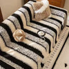 A bohemian striped jacquard sofa throw featuring black and cream stripes with a fluffy accent pillow.