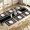 A wooden dining table set with black and white geometric placemats and tableware.