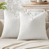 A close-up of a white breathable chenille pillow cover with a minimalist chevron design resting on a light-colored surface.