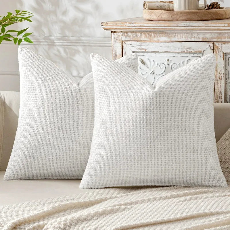 A close-up of a white breathable chenille pillow cover with a minimalist chevron design resting on a light-colored surface.