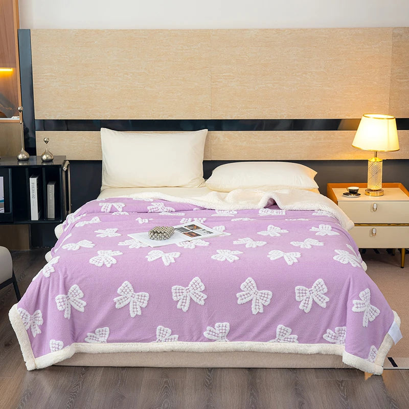 A purple blanket with white bow patterns is displayed on a bed in a modern room.