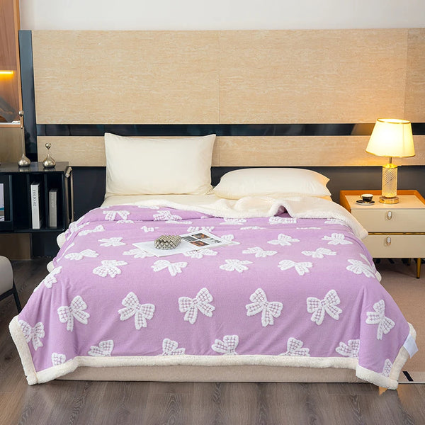 A purple blanket with white bow patterns is displayed on a bed in a modern room.