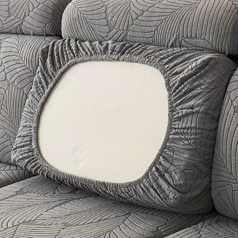 A close-up of a gray leaf pattern sofa slipcover featuring a square cutout revealing a white cushion.