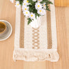 Boho linen cotton table runner with beige stripes and tassels featuring a white flower arrangement.