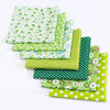 A stack of green and white floral dot pattern cotton fabric squares for DIY crafting.