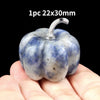 A handcrafted natural stone pumpkin figurine with a silver stem is held in a person's hand.