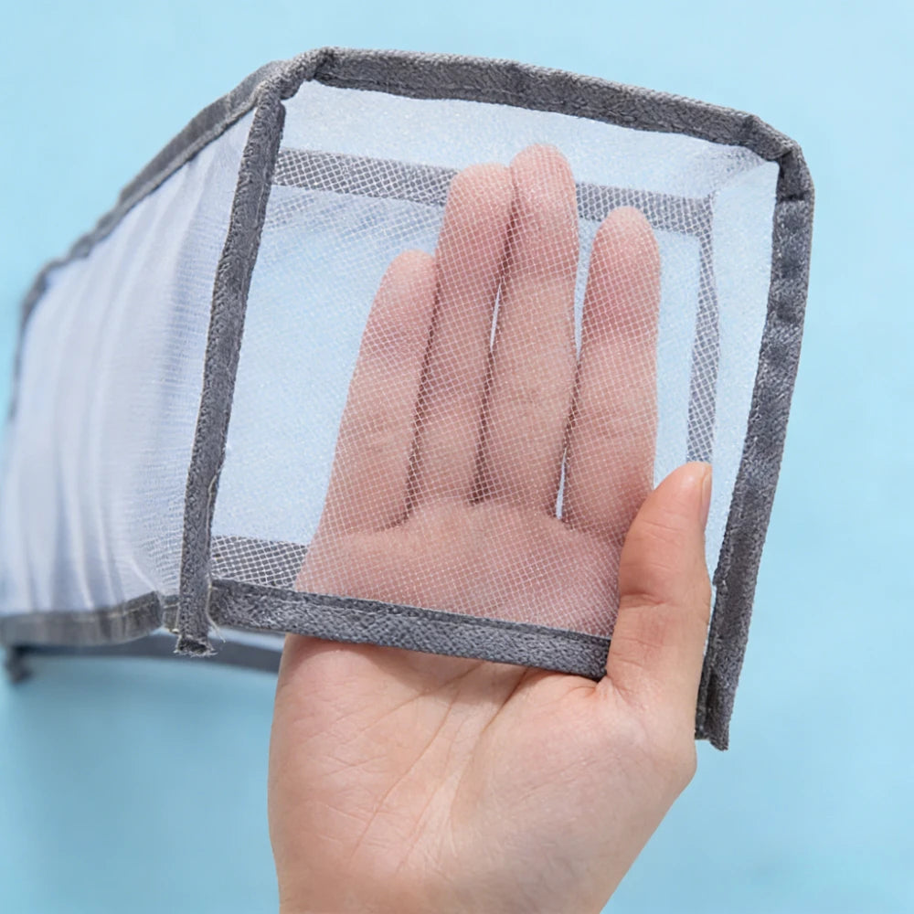 A hand is holding a clear mesh foldable drawer organizer for undergarments and accessories.