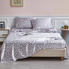 A bed featuring a leopard print satin sheet set with gray and white patterns.