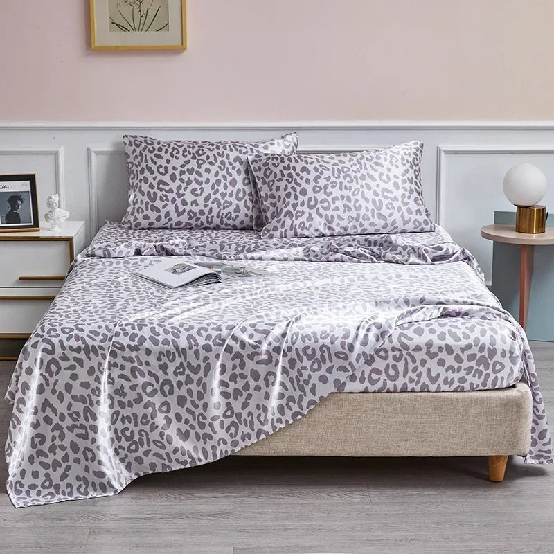 A bed featuring a leopard print satin sheet set with gray and white patterns.