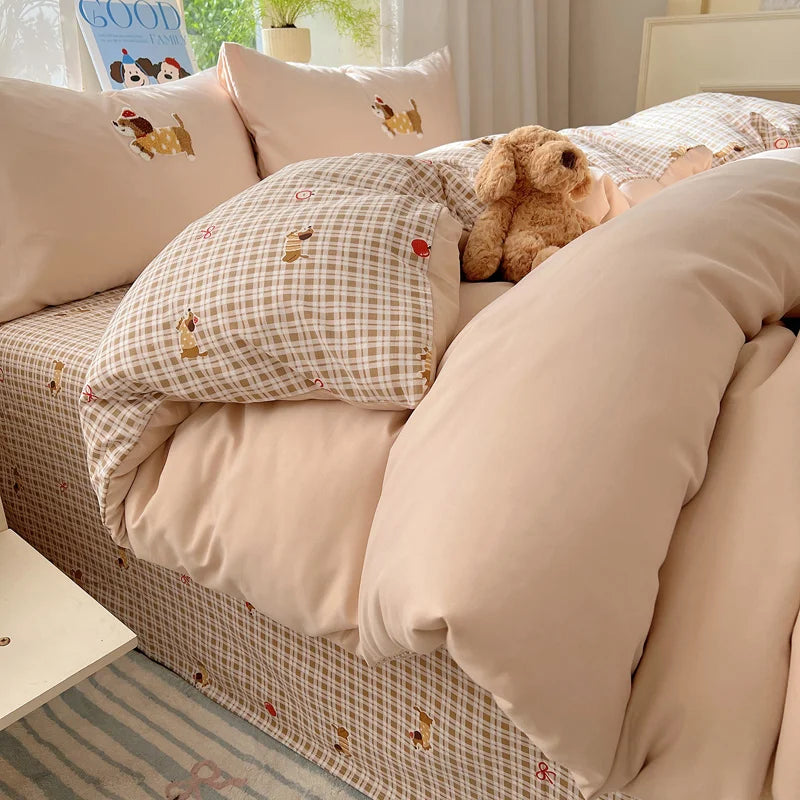 A beige and brown cartoon embroidered bedding set featuring pillows and a duvet on a bed.